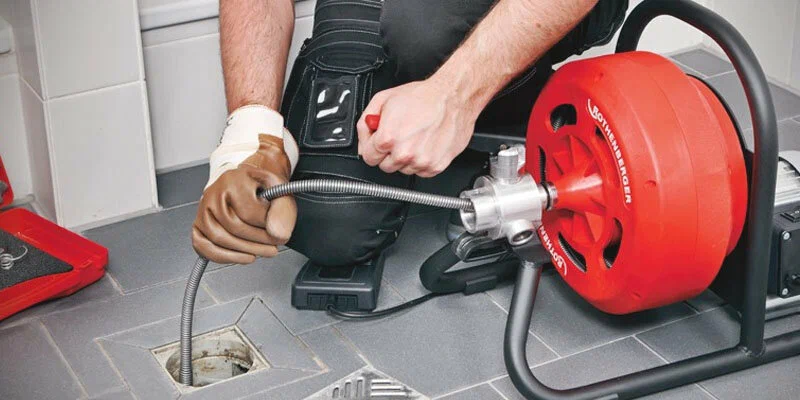 Plumber using a drain-cleaning machine in Lancaster