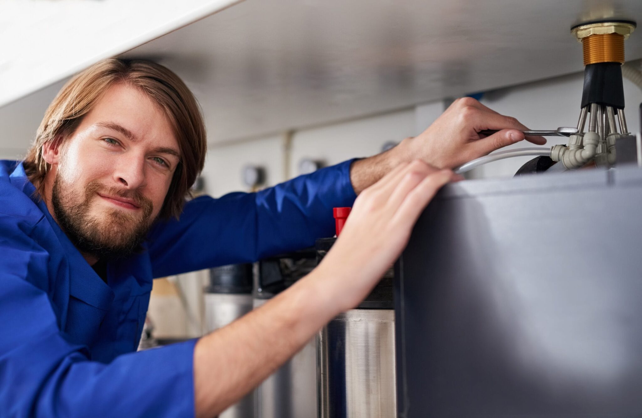 Technician servicing a residential water heater tank in Lancaster